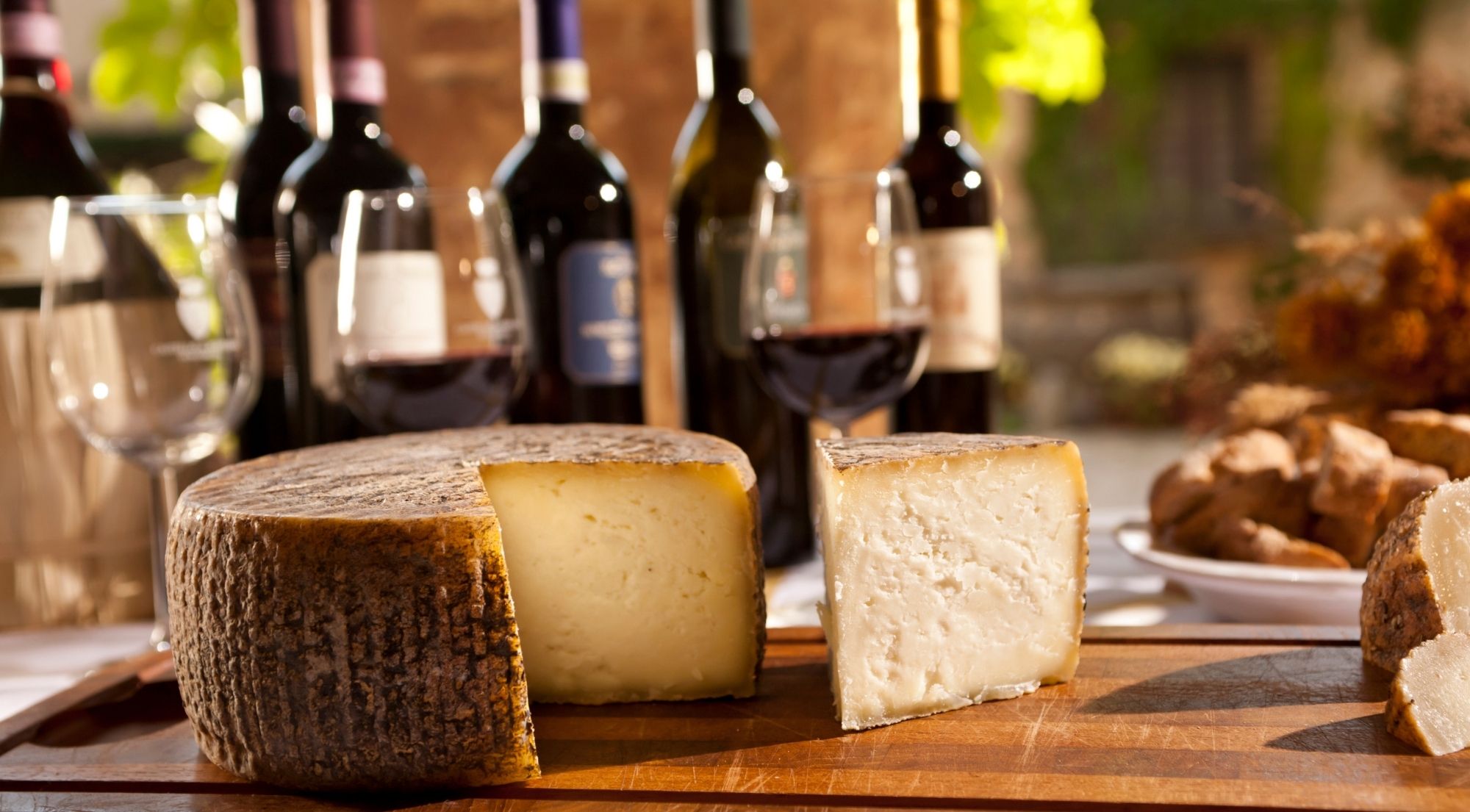 Wheel of aged Pienza pecorino with Chianti bottles, open glasses and bread