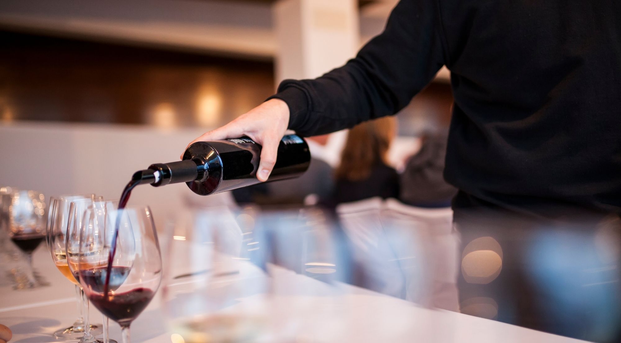 A sommelier pouring Chianti Classico into a row of glasses at a tasting